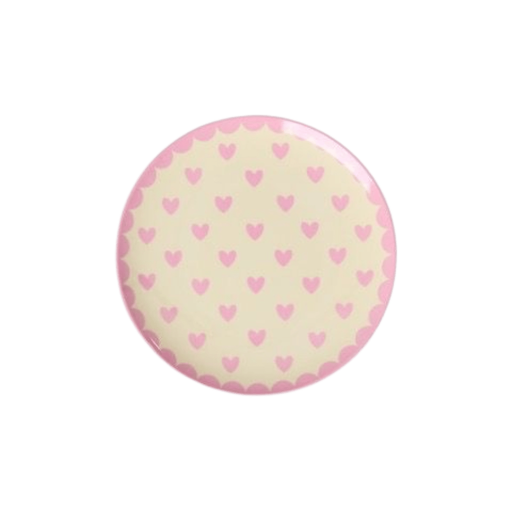 Small round cream melamine cake plate with rows of pink hearts and a pink scalloped edge, top view