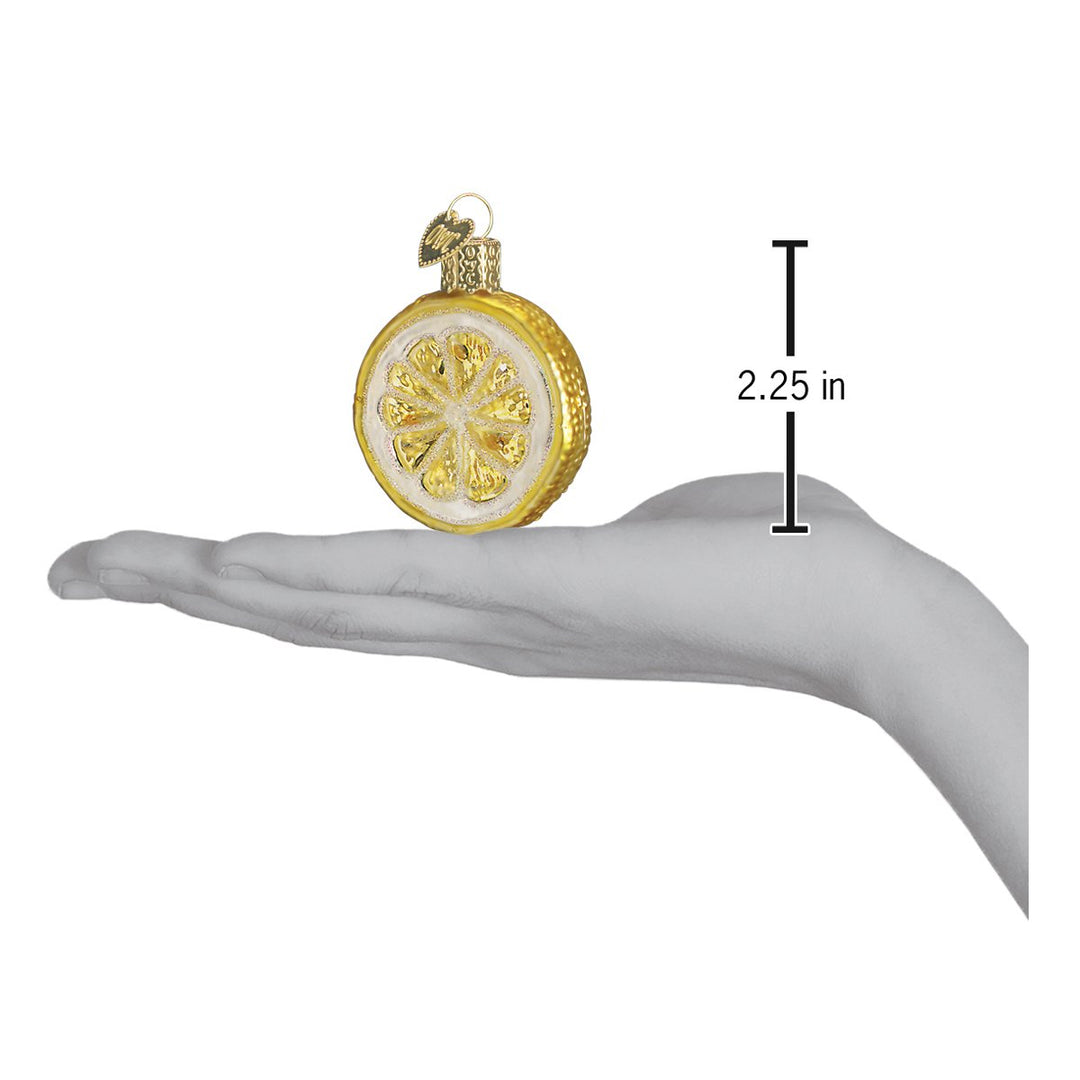 Lemon slice ornament on an open palm beside a 2.25 inch height marker for scale