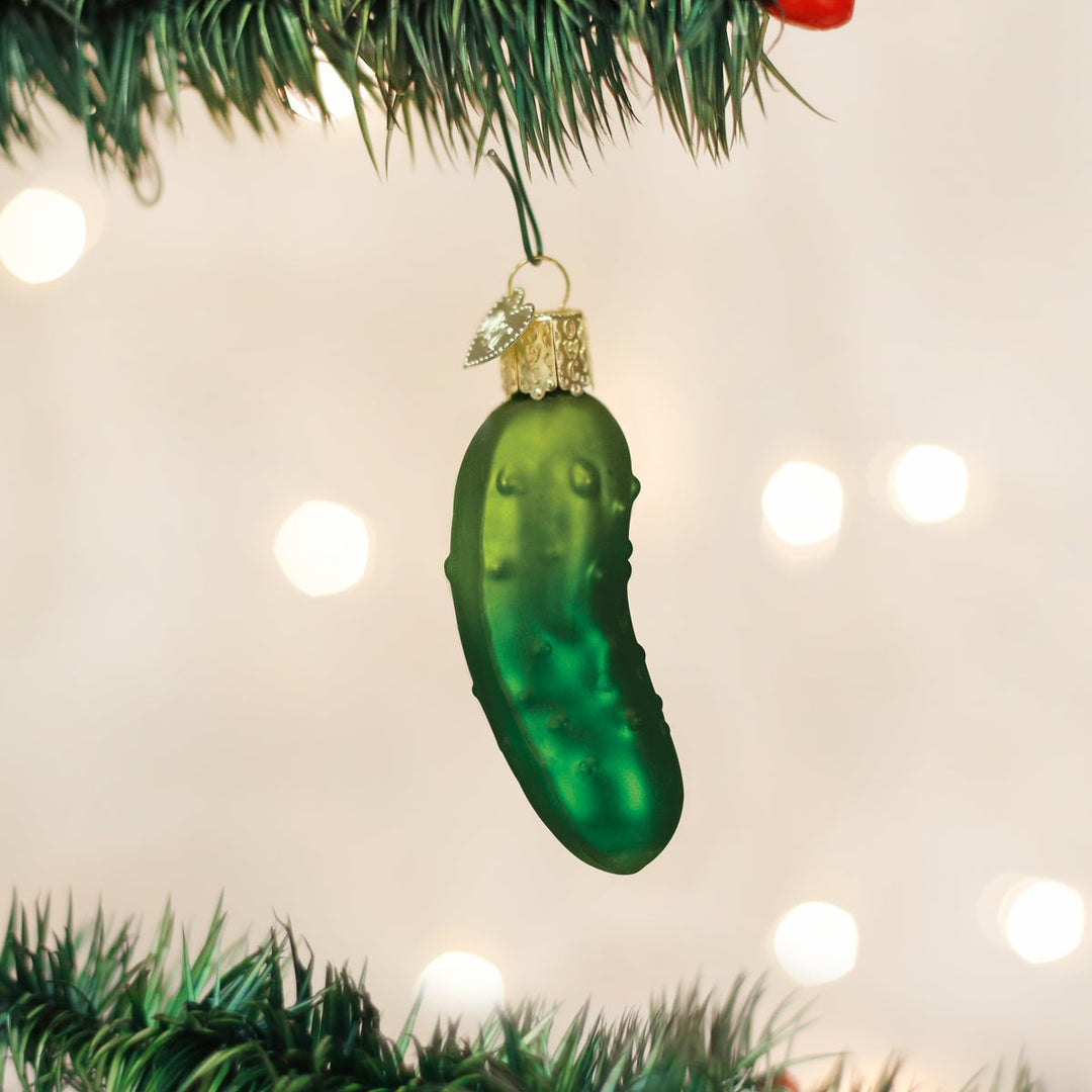 Christmas pickle ornament hanging among the branches of a lit Christmas tree