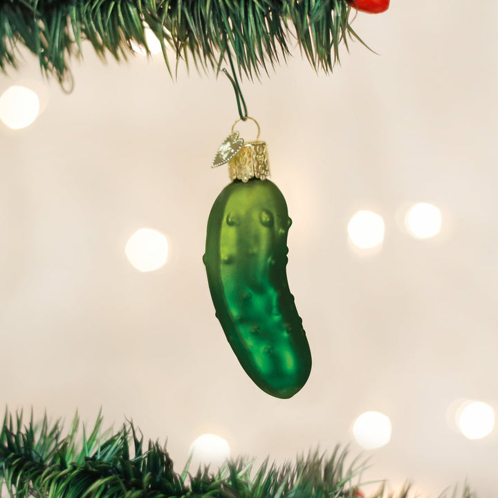 Christmas pickle ornament hanging among the branches of a lit Christmas tree