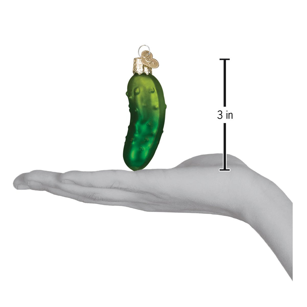 Christmas pickle ornament on an open palm beside a 3 inch height marker