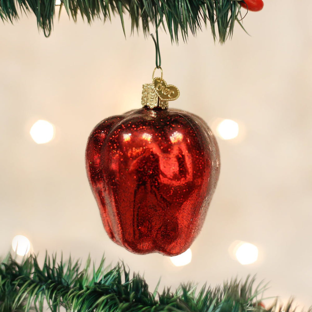 Red apple ornament hanging on a pine branch with warm twinkle lights, a sweet gift for teachers