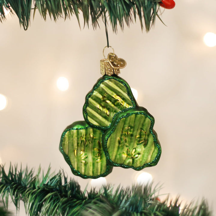 Pickle chips glass ornament hanging from a lit Christmas tree