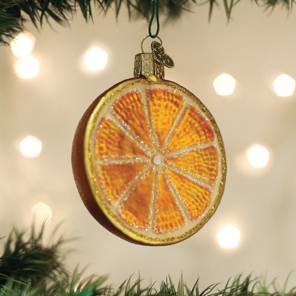 Orange slice ornament hanging on a lit Christmas tree with warm bokeh lights
