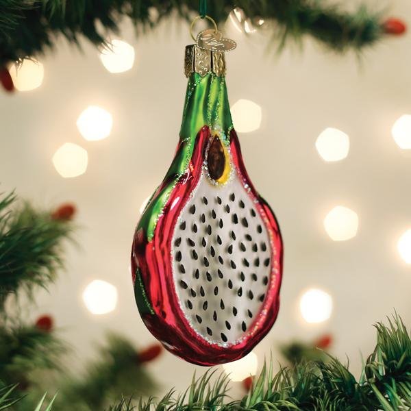 Dragon fruit ornament hanging on a lit Christmas tree with warm bokeh lights