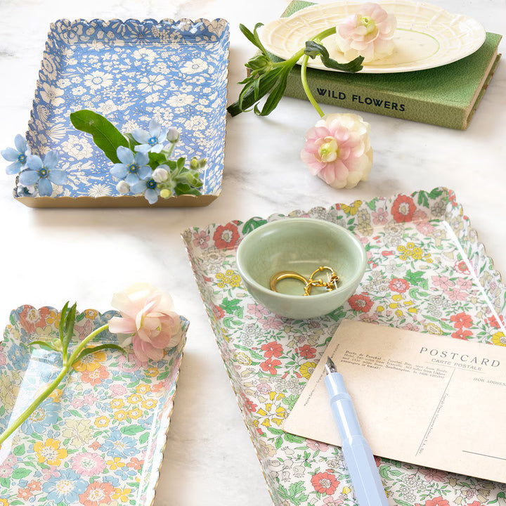 Meri Meri x Liberty floral metal accessory trays with scalloped edges, styled with jewelry, flowers, and stationery.