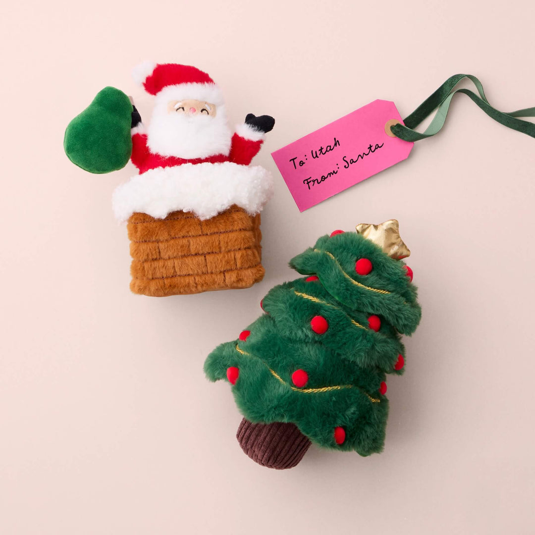 Santa chimney and Christmas tree plush dog toys beside a pink To Utah, From Santa gift tag.