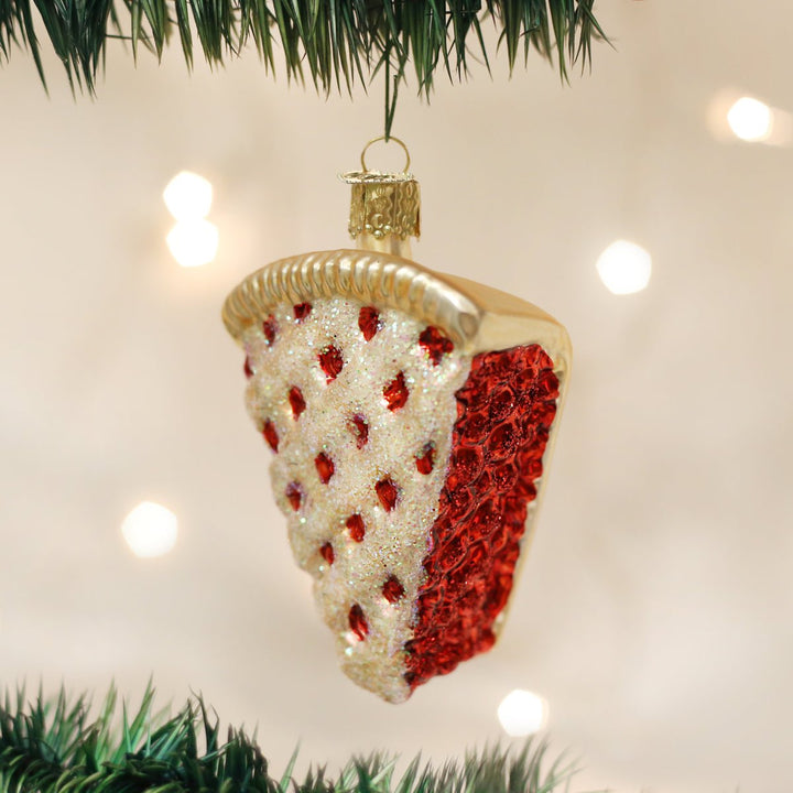 Cherry pie slice glass ornament hanging on a lit Christmas tree