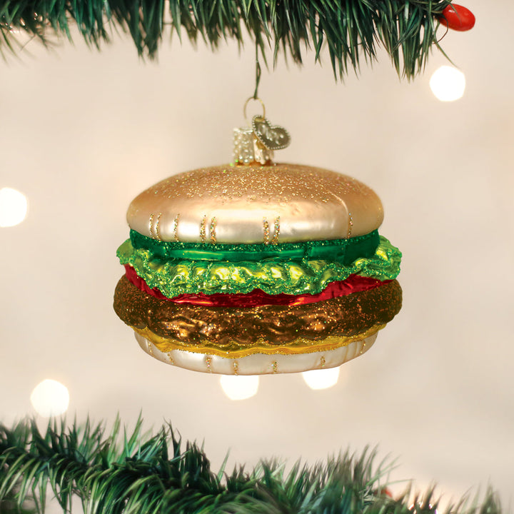 Cheeseburger glass ornament hanging on a Christmas tree with warm bokeh lights