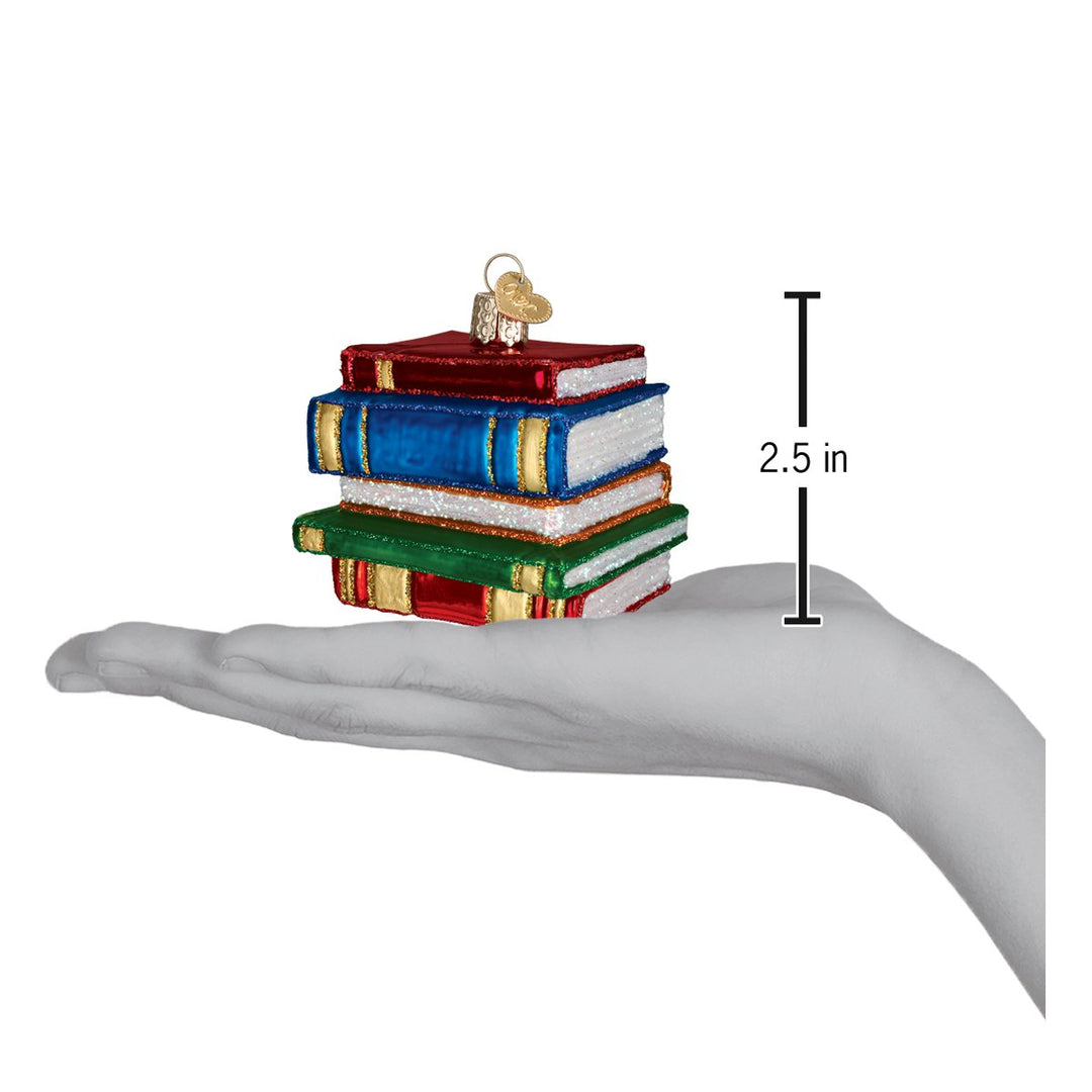 Stack of books ornament held above an open palm with a 2.5 inch height marker for scale