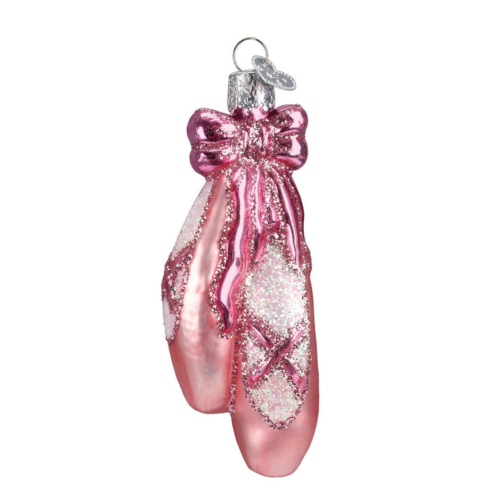 Pair of pink pointe shoe ballet slippers glass ornament with crisscross ribbons and a pink bow, on white