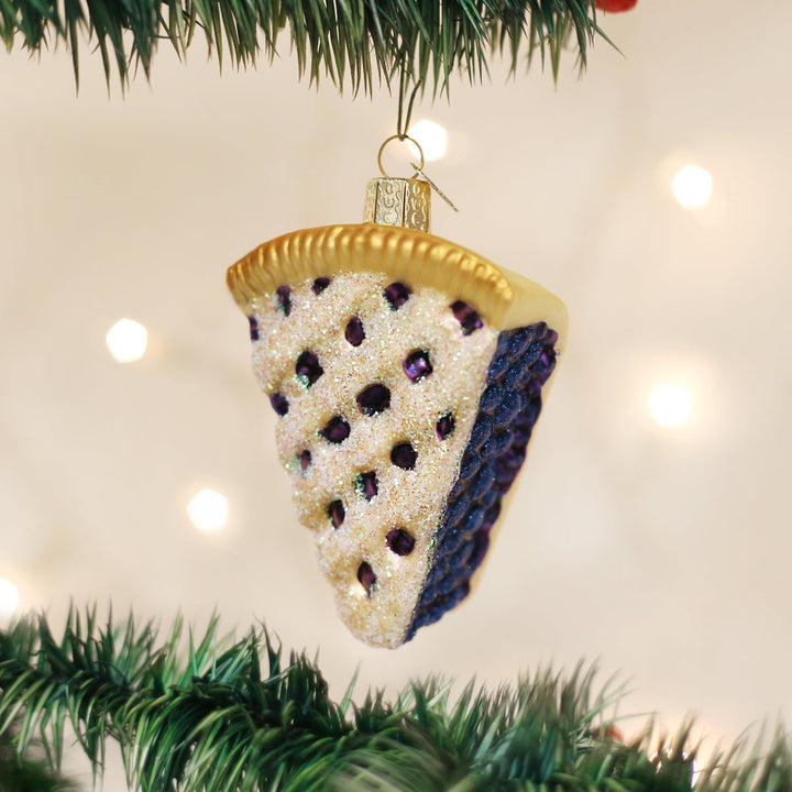 Blueberry pie slice glass ornament hanging on a Christmas tree with bokeh lights