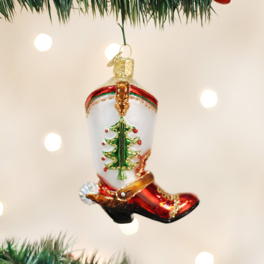 Christmas tree cowboy boot ornament hanging on a lit Christmas tree with warm bokeh lights