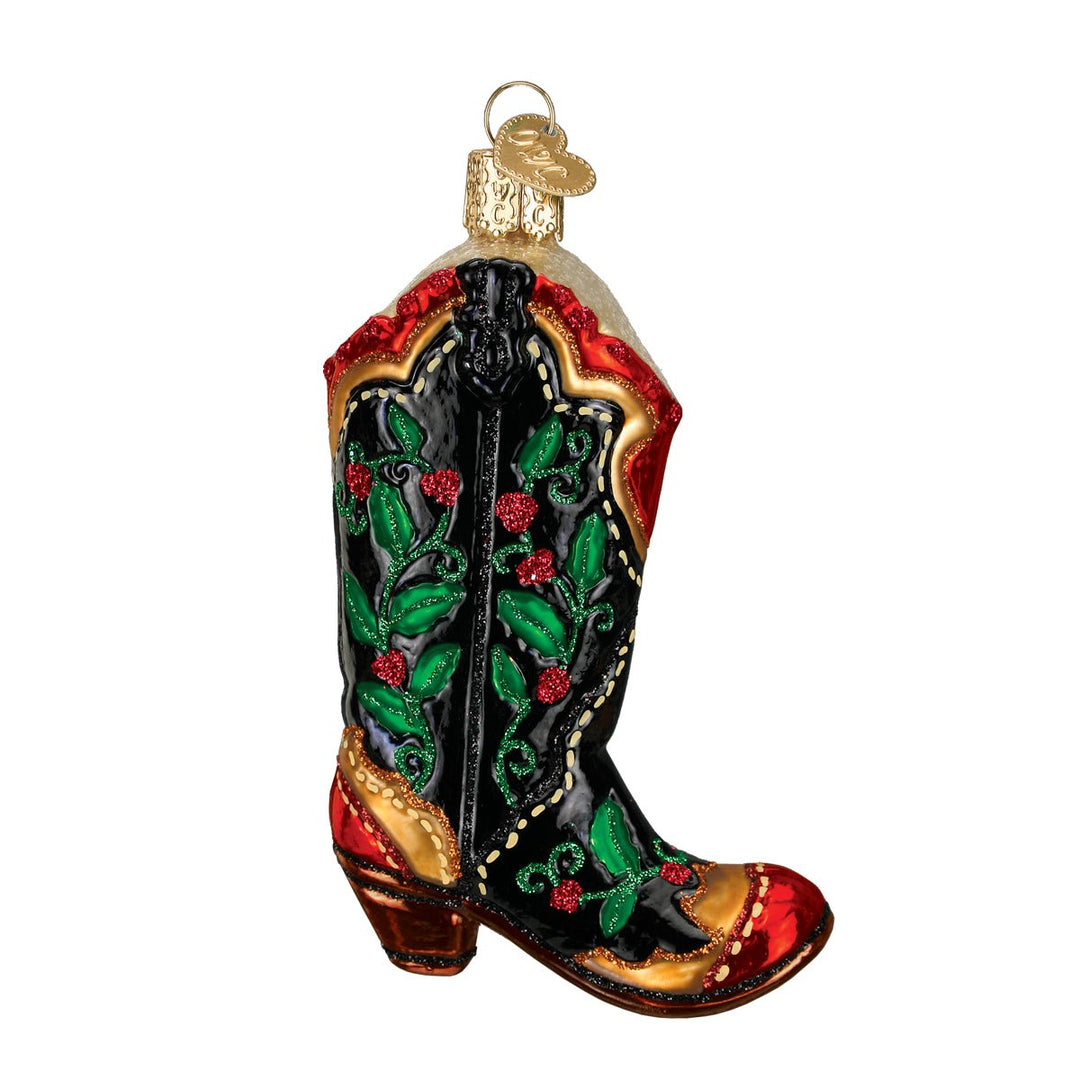 Black cowboy boot ornament with green holly leaves, red berries, gold stitching, and a red toe, on white