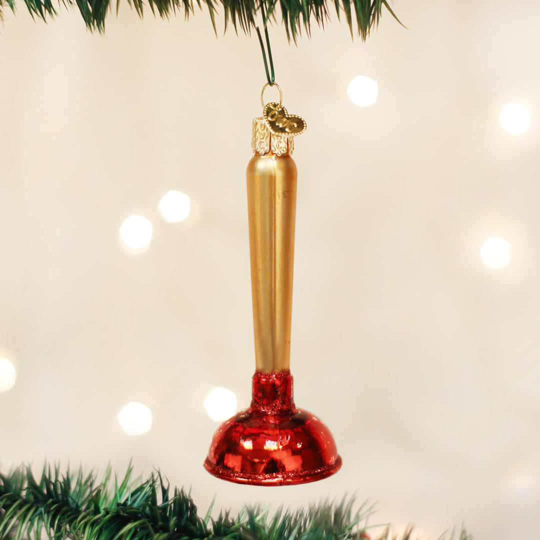 Toilet plunger funny Christmas ornament hanging on a tree branch with warm bokeh lights