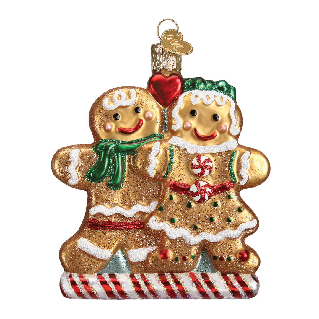 Front of the gingerbread friends ornament, two cookies in a green scarf and bow with a red heart, on white