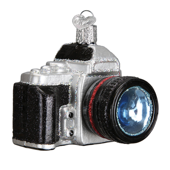 Black and silver camera ornament with a red lens ring and blue glass lens on a white background