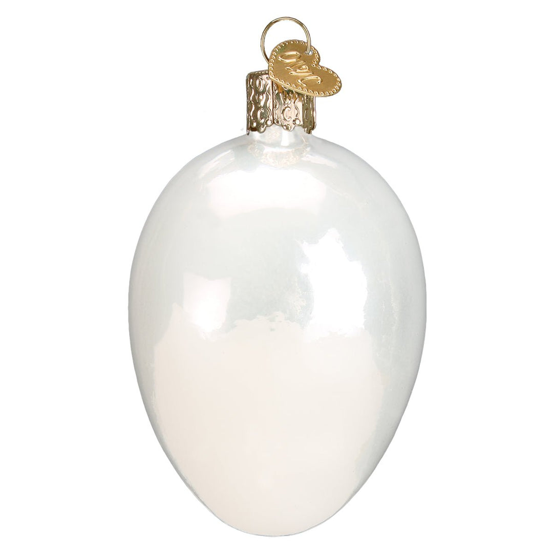 Back of the deviled egg ornament with a smooth pearly white shell and gold cap, on white