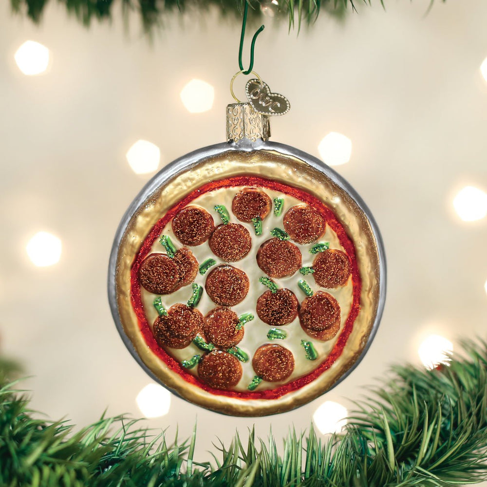 Pepperoni pizza glass ornament hanging on a Christmas tree with warm lights