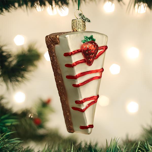 Cheesecake slice glass ornament hanging on a lit Christmas tree, point down