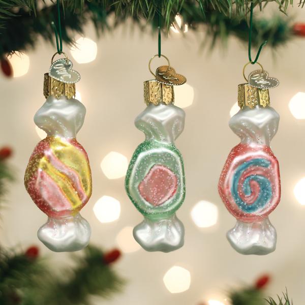 Three salt water taffy ornaments hanging together on a Christmas tree with soft bokeh lights