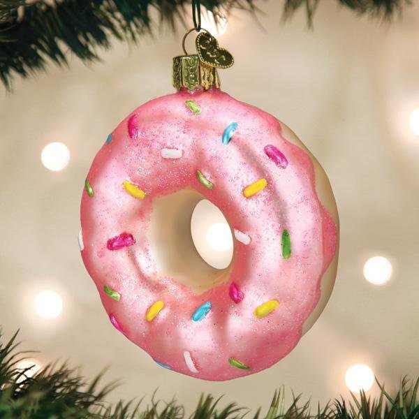 Pink sprinkle donut glass ornament hanging on a lit Christmas tree