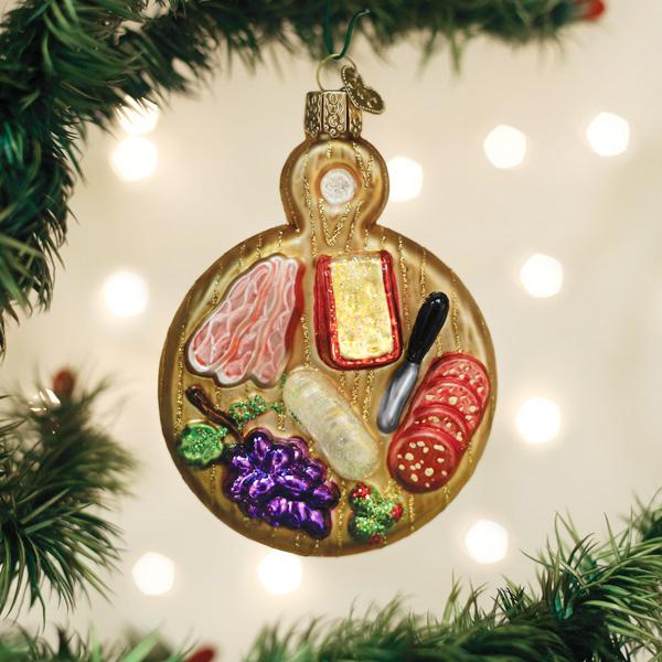 Charcuterie board glass ornament hanging on a Christmas tree with glowing bokeh lights for a host