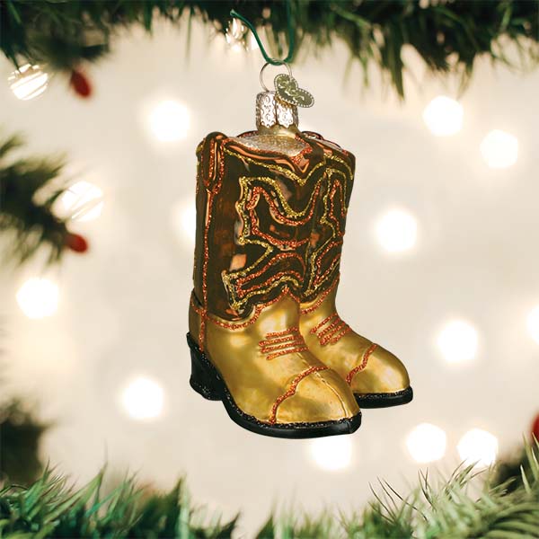 Brown cowboy boots ornament hanging on a lit Christmas tree with soft bokeh lights