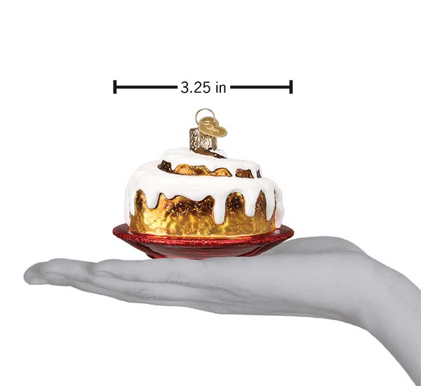 Cinnamon roll ornament on an open palm under a 3.25 inch width marker for scale