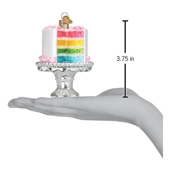 Rainbow cake on stand ornament on an open palm beside a 3.75 inch height marker