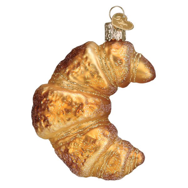 Croissant ornament in golden glittered glass with flaky rolled layers, front view on white