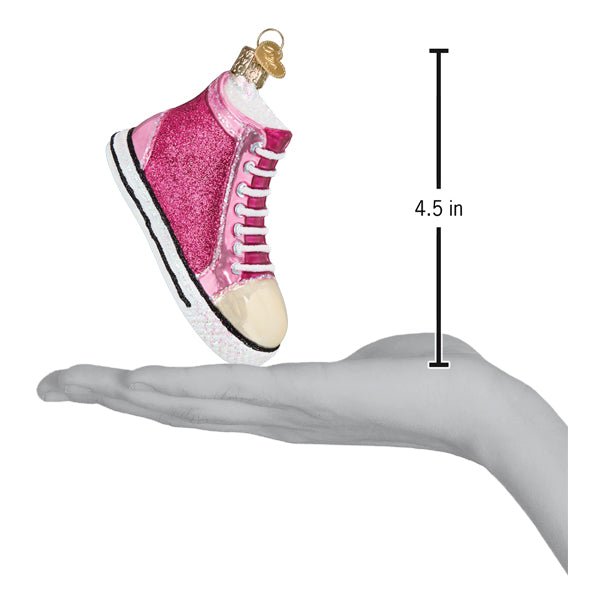 Pink sneaker ornament resting on an open hand with a 4.5 inch scale marker beside it