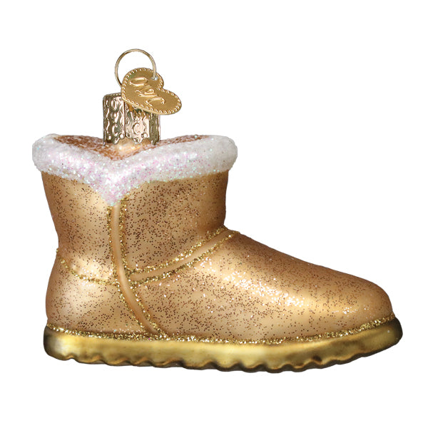 Side view of the tan glitter sheepskin boot glass ornament with white fur cuff and gold sole, on white