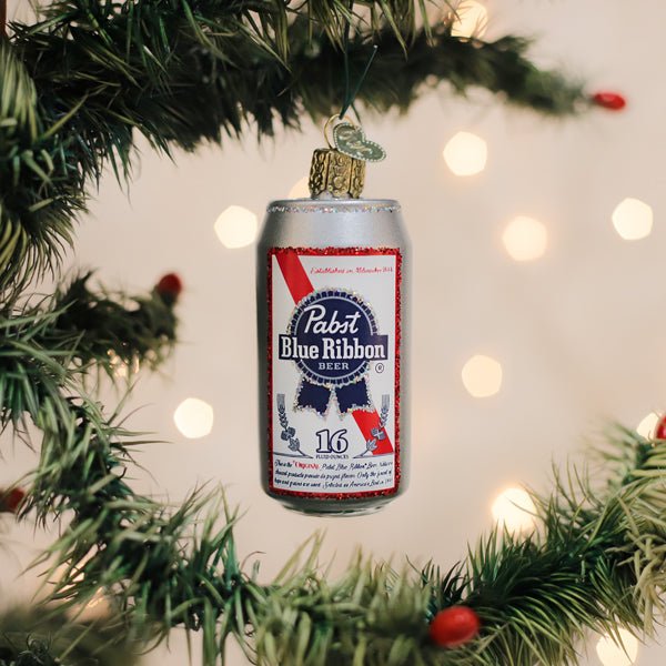 Silver Pabst Blue Ribbon can ornament hanging on a lit Christmas tree with warm bokeh lights