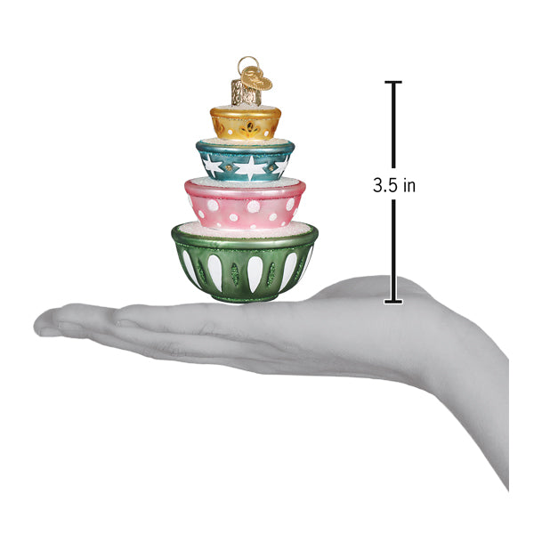 Stacked mixing bowls ornament resting on an open palm beside a 3.5 inch height marker for scale