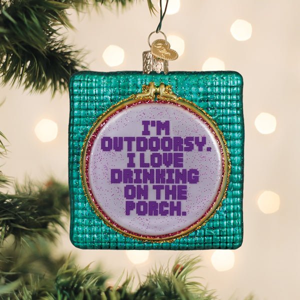 I'm Outdoorsy embroidery hoop ornament hanging on a lit Christmas tree with warm bokeh lights