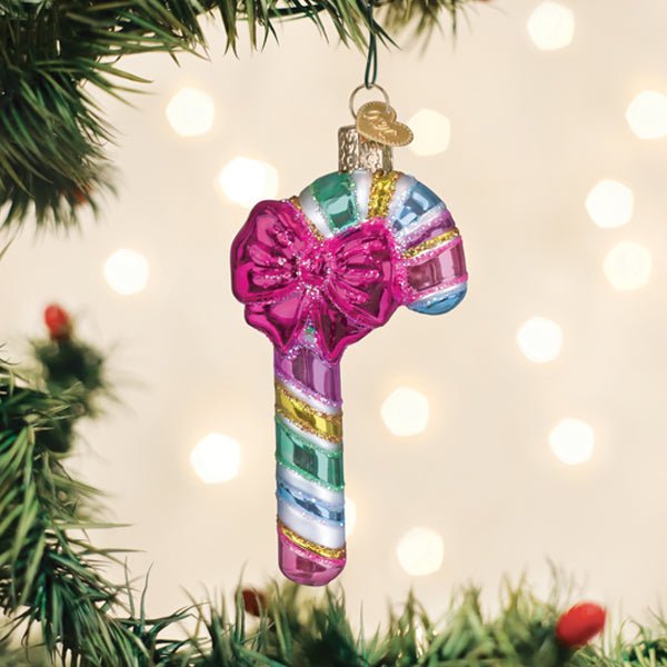 Pastel candy cane ornament with pink bow hanging on a Christmas tree with soft bokeh lights
