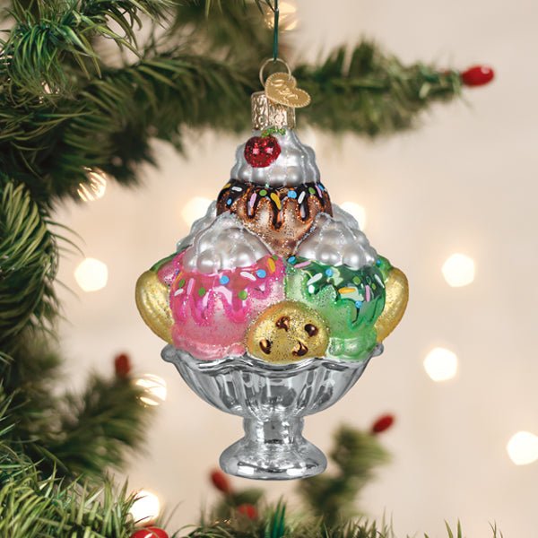Ice cream sundae ornament hanging on a lit Christmas tree with warm bokeh lights and red berries