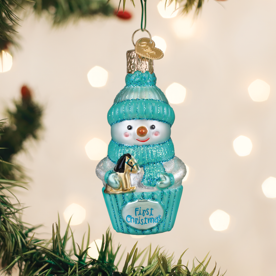 Aqua snow baby first Christmas glass ornament hanging on a lit Christmas tree