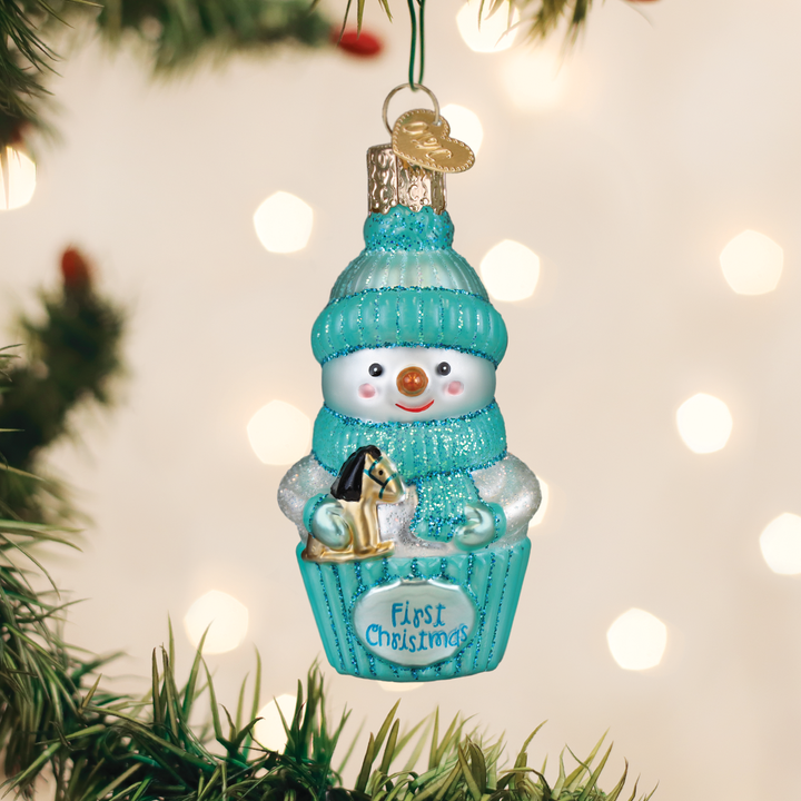 Aqua snow baby first Christmas glass ornament hanging on a lit Christmas tree