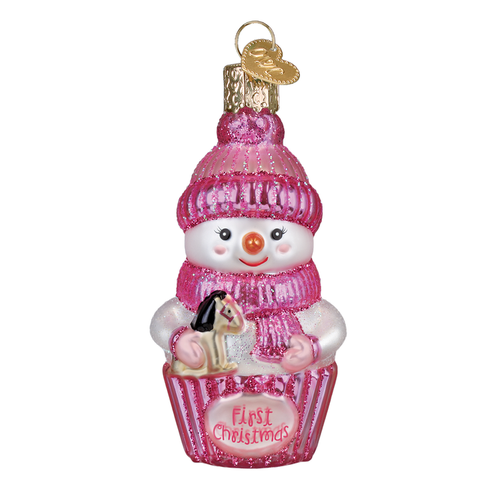 Pink snow baby ornament in a knit hat holding a rocking horse in a First Christmas cupcake, on white