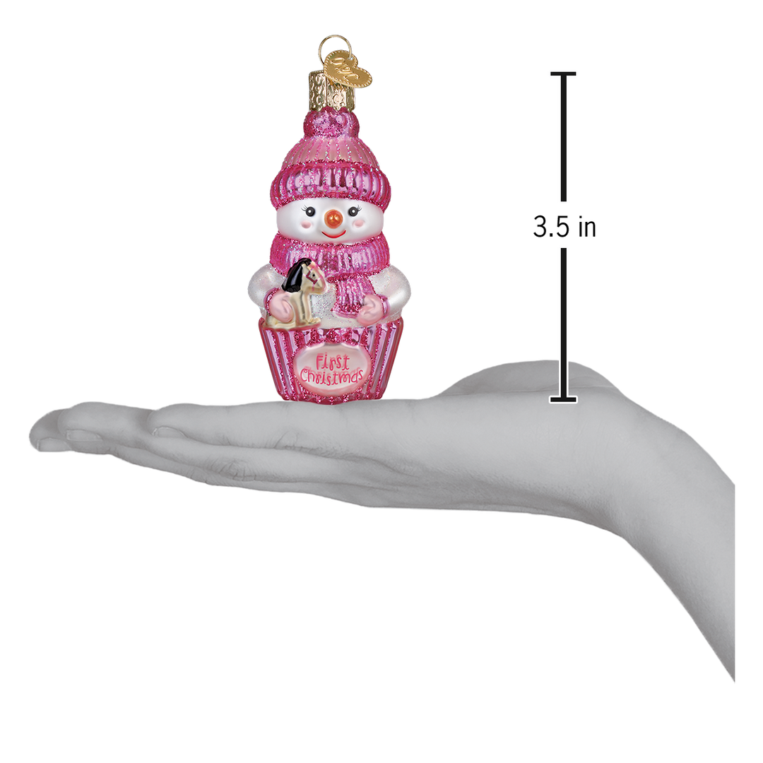 Pink snow baby ornament on an open palm beside a 3.5 inch height marker