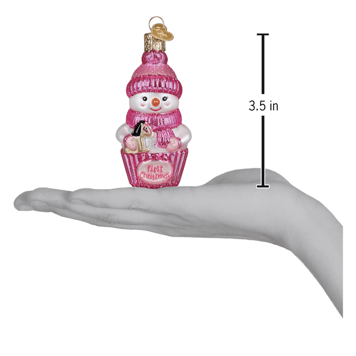Pink snow baby ornament on an open palm beside a 3.5 inch height marker