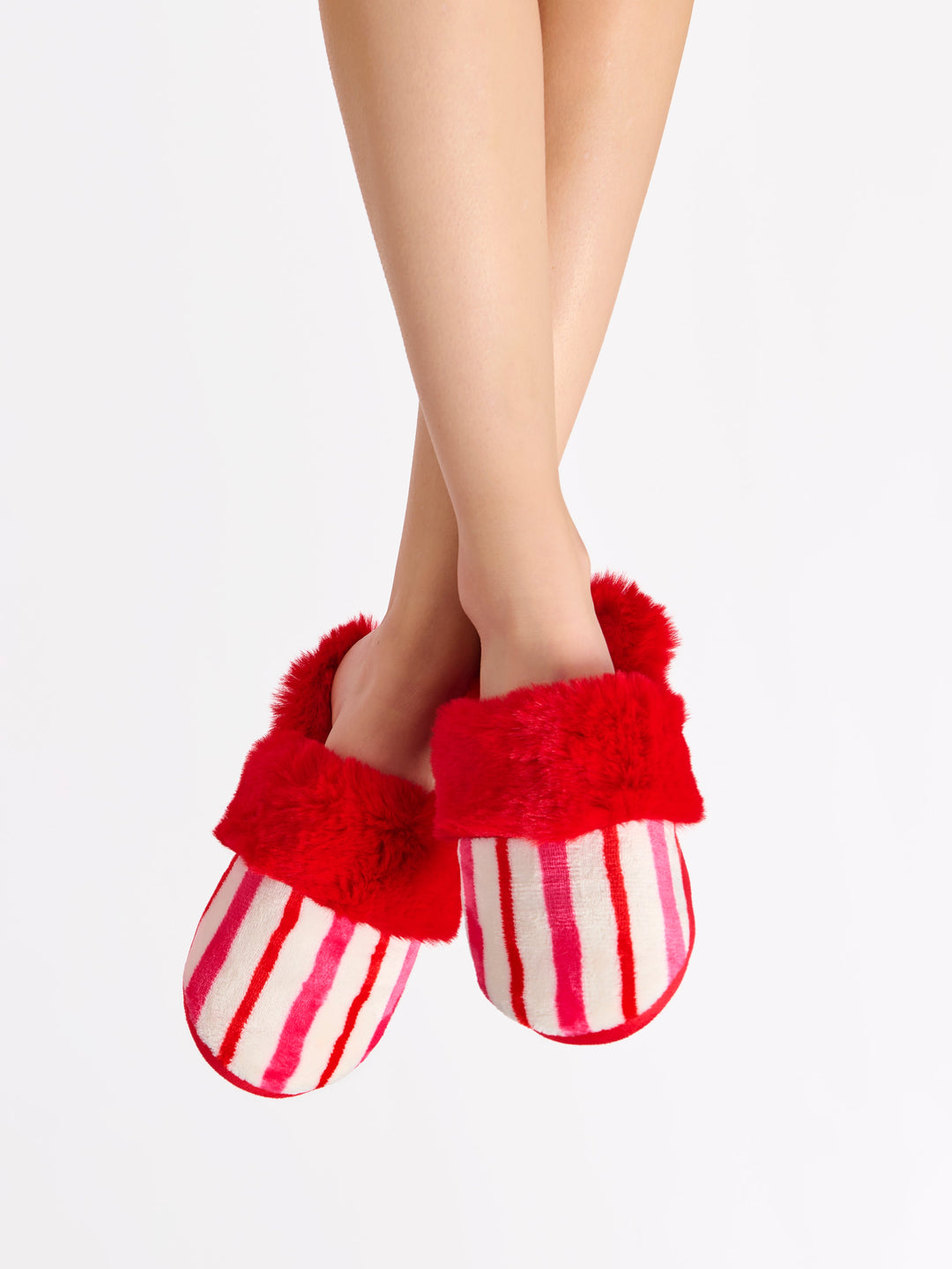 Crossed legs wearing candy stripe slippers with red faux fur