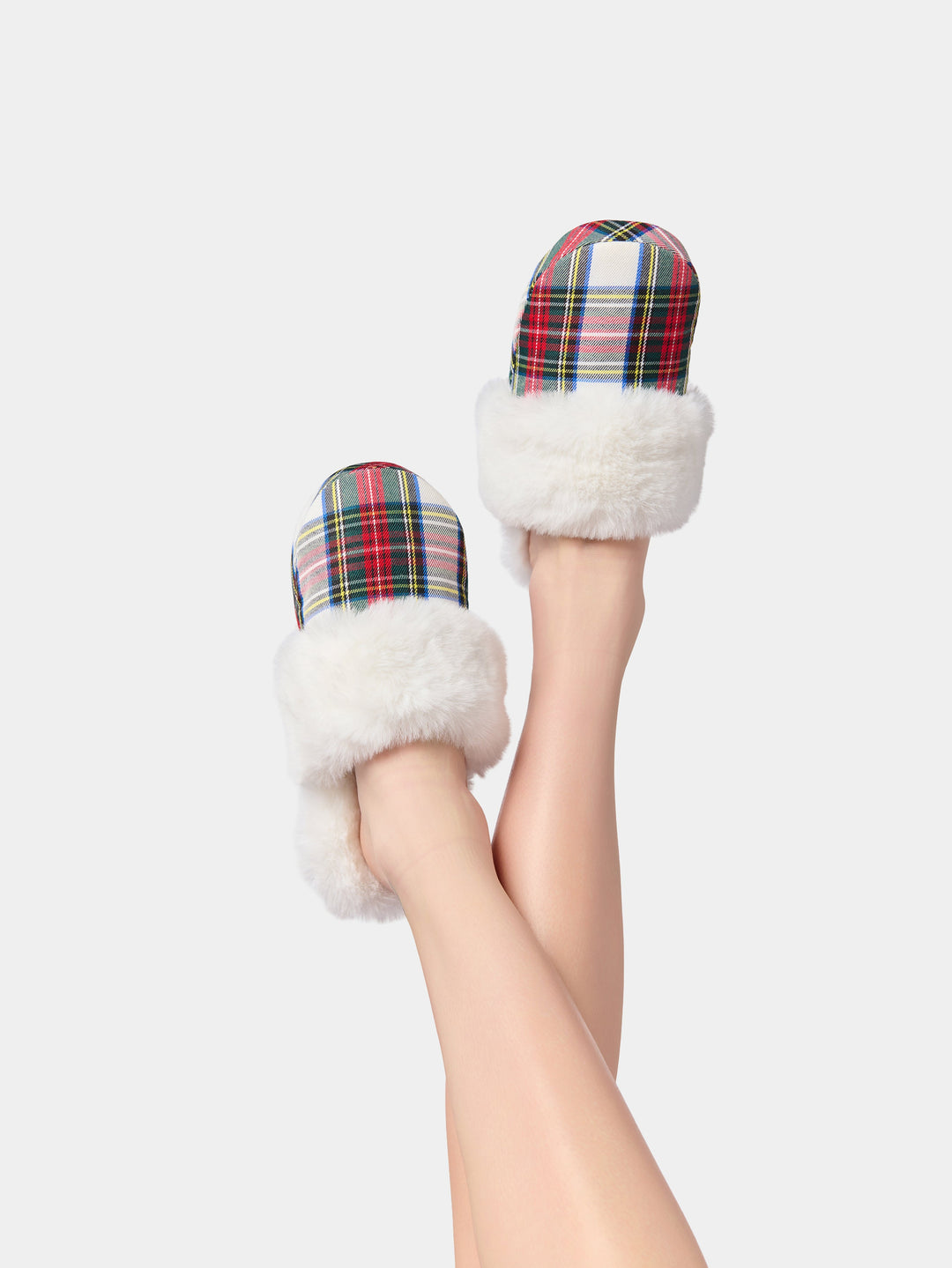 Legs raised wearing white faux fur slippers with red plaid