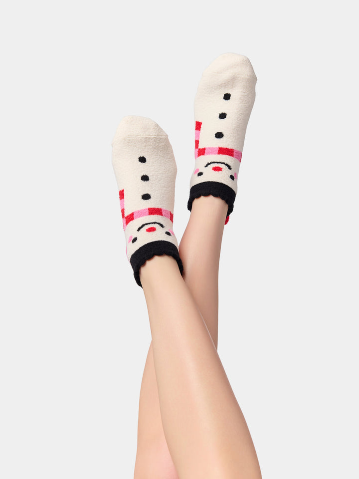 Legs raised wearing ivory snowman fuzzy socks