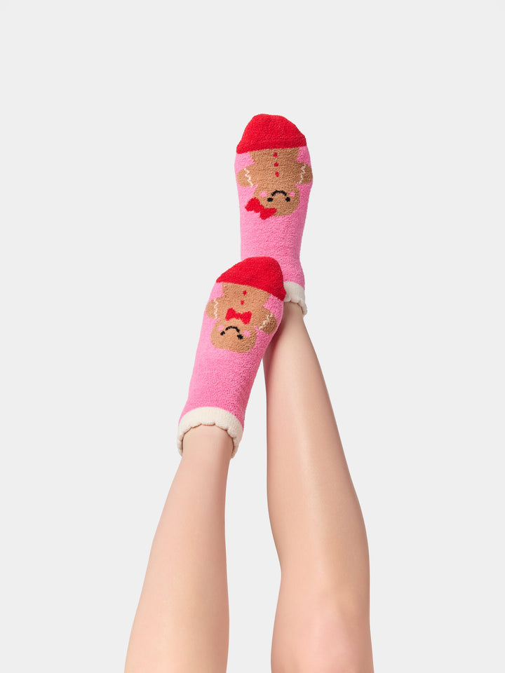 Legs raised wearing pink gingerbread fuzzy socks
