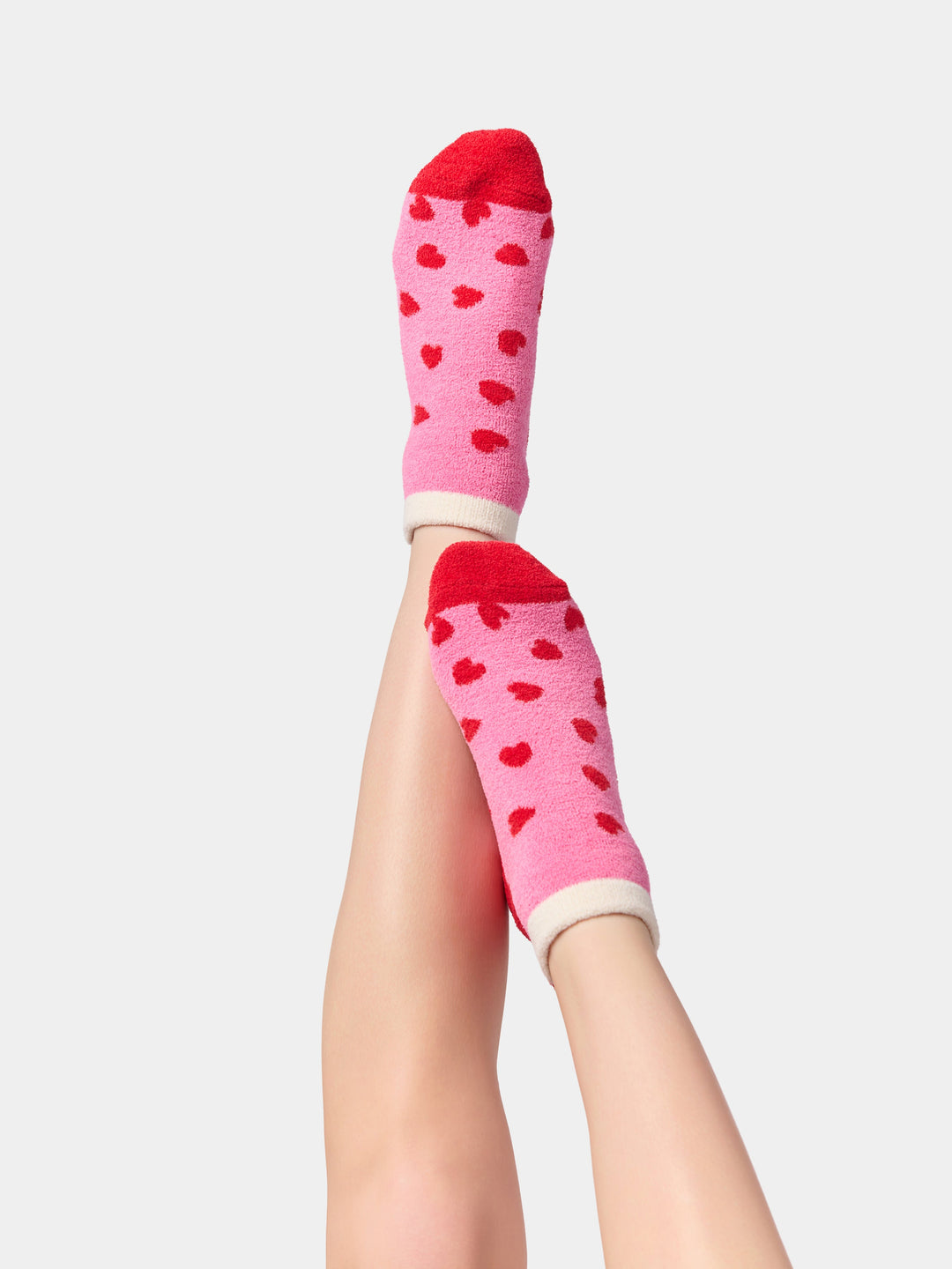 Legs raised wearing pink socks with tiny red hearts