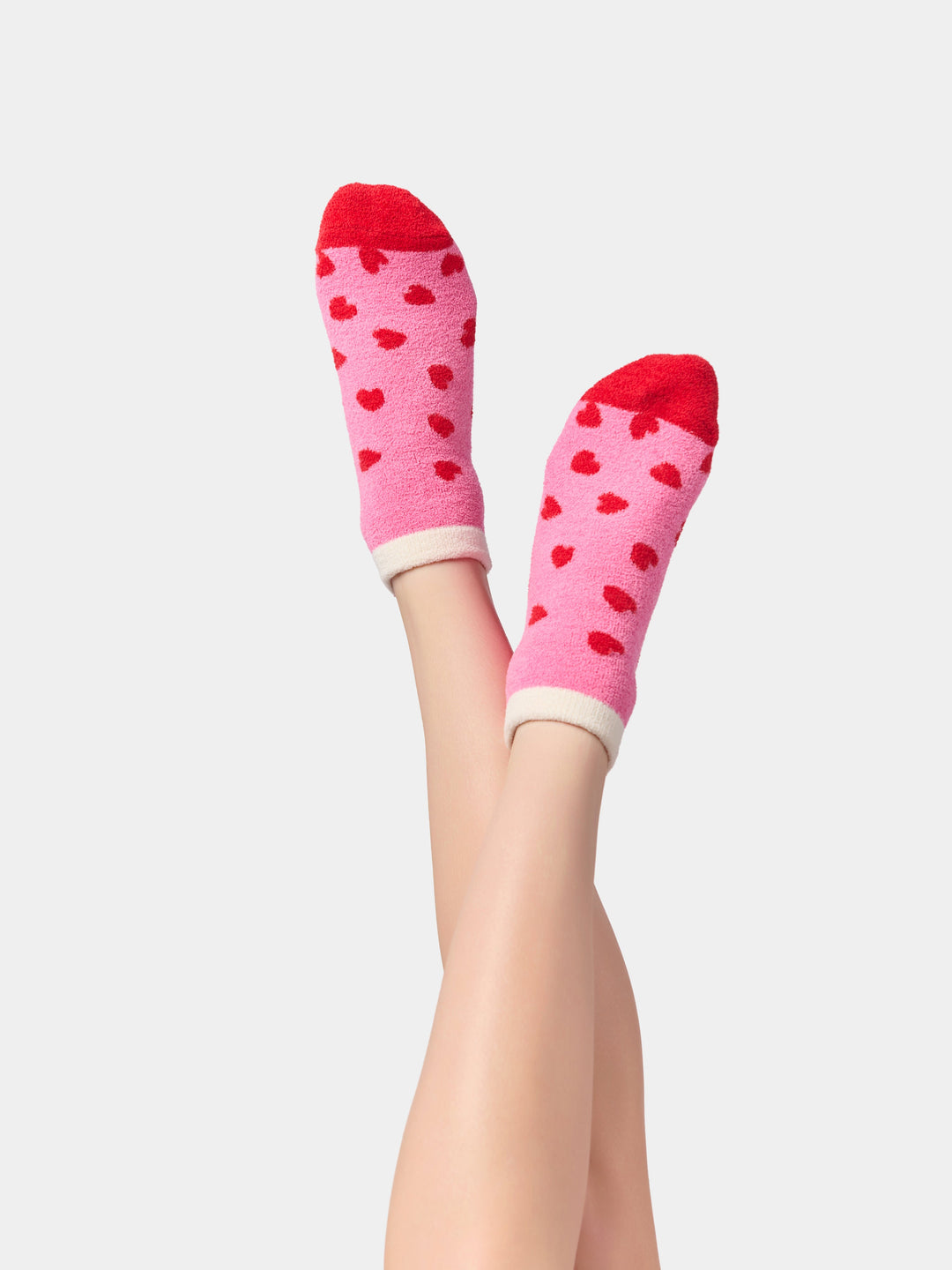 Pink heart socks on raised feet showing red toes