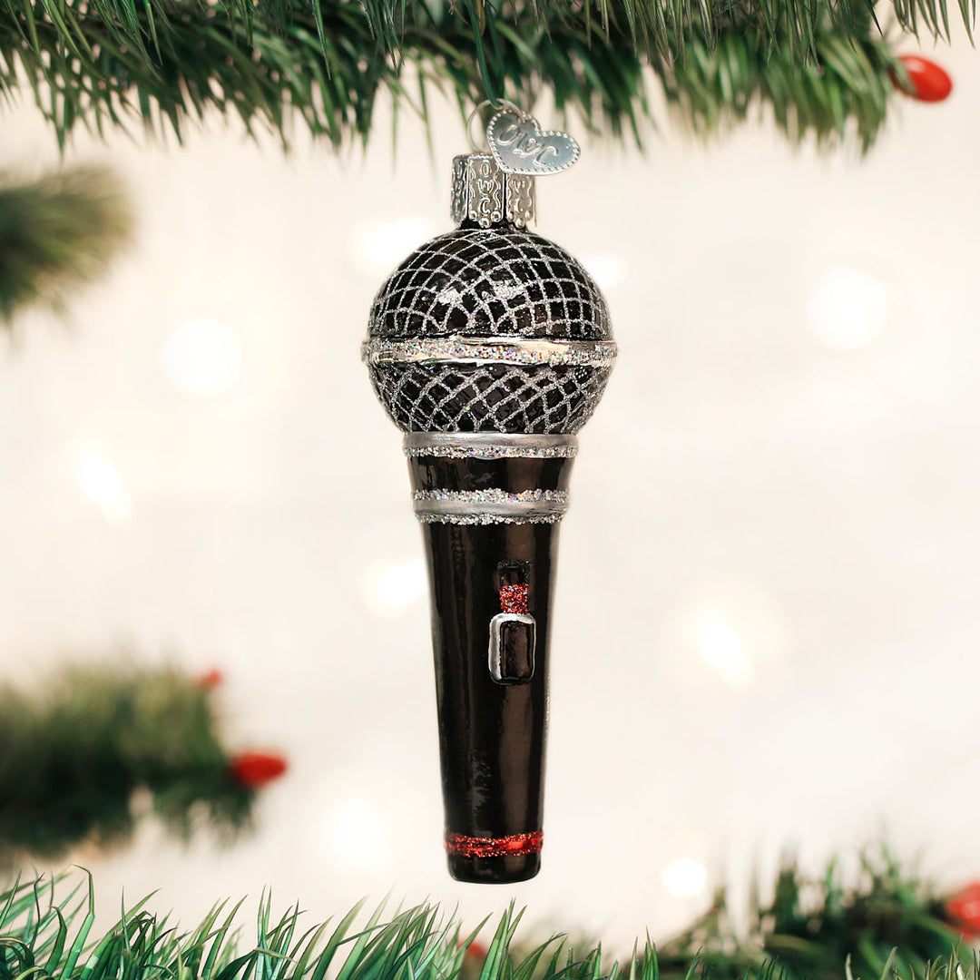 Microphone ornament hanging on a lit Christmas tree with warm bokeh lights